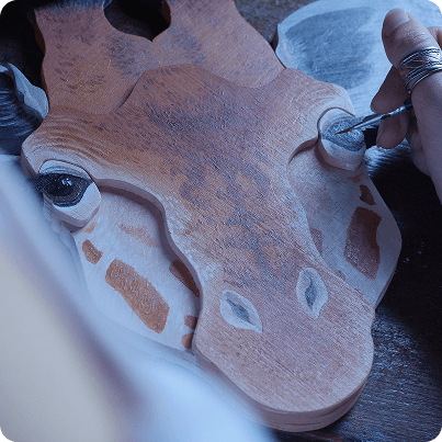Découpe de girafe en bois en cours de peinture dans l'atelier